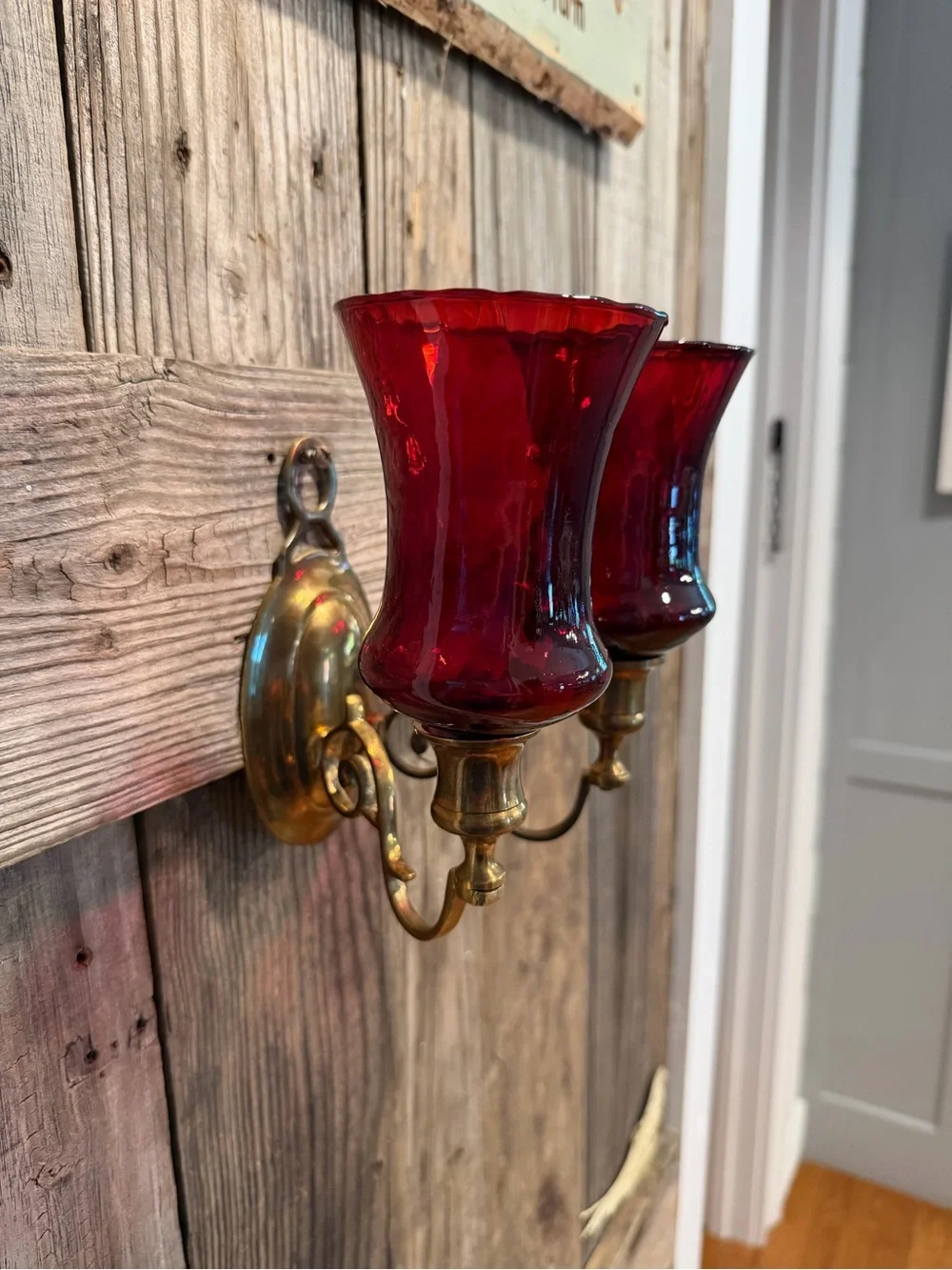 Vintage double-arm brass wall sconce fitted with ruby red votive cups